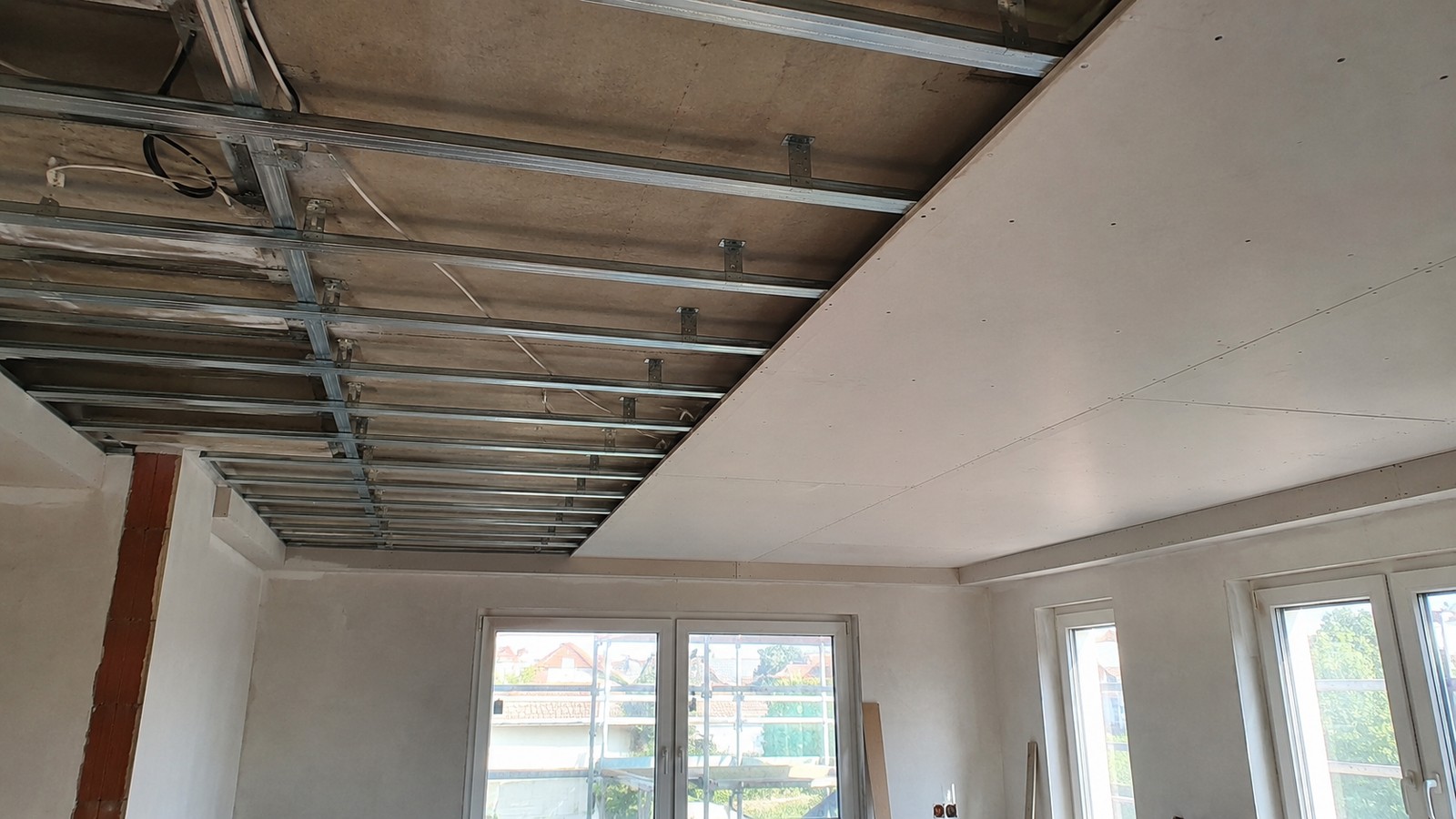 Abgehängte Decke im Bau: Metall-Unterkonstruktion sichtbar, ein Teil der Fläche bereits mit Gipsplatten geschlossen