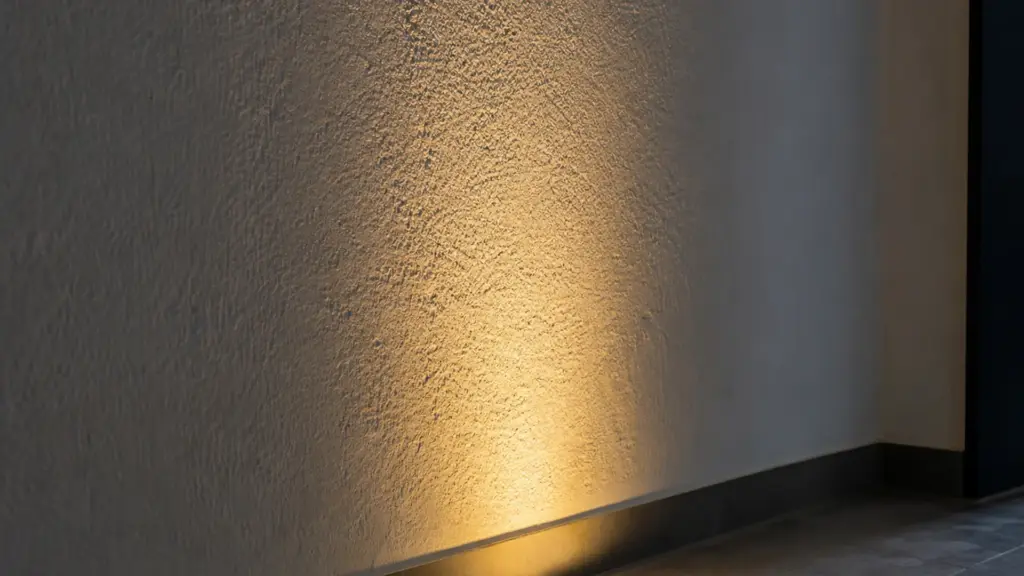 Licht streicht von unten an einer strukturierten Wand entlang und betont die Oberfläche