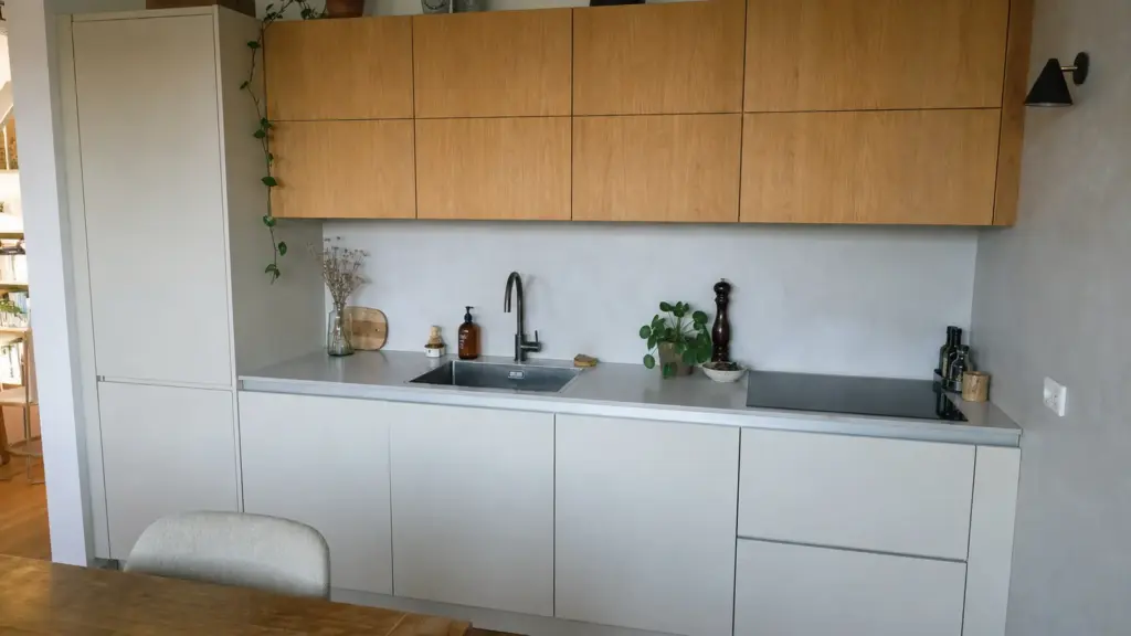 Blick entlang einer Küchenzeile von Kühlschrank über Spüle bis zum Kochfeld mit freien Abstellflächen dazwischen