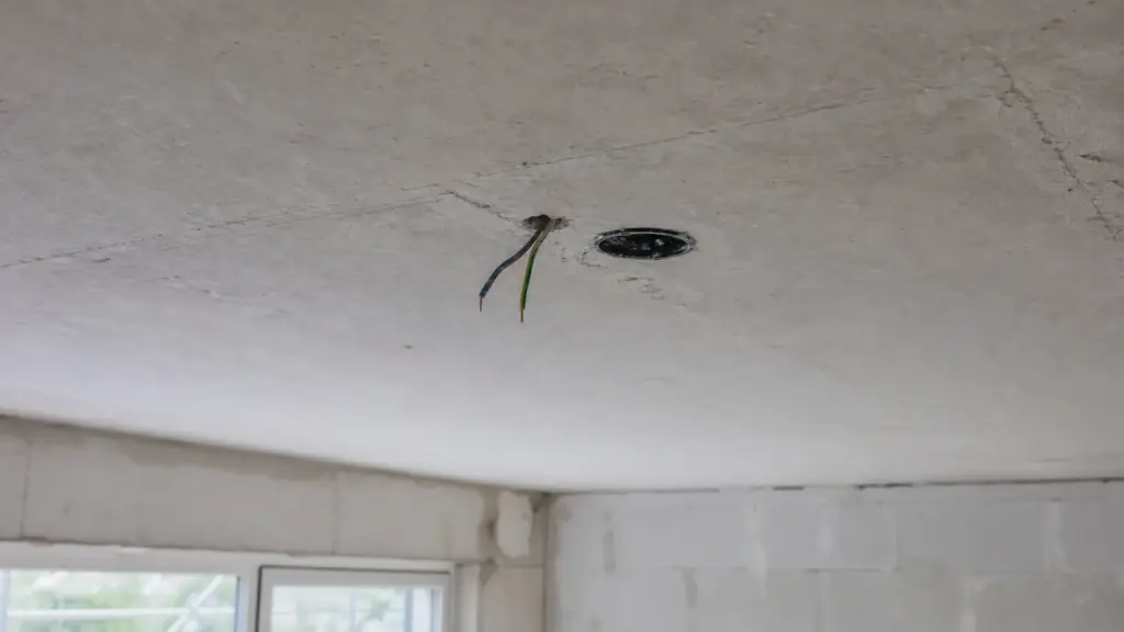 Deckenauslass mit herausstehendem Kabel in einer unverputzten Decke