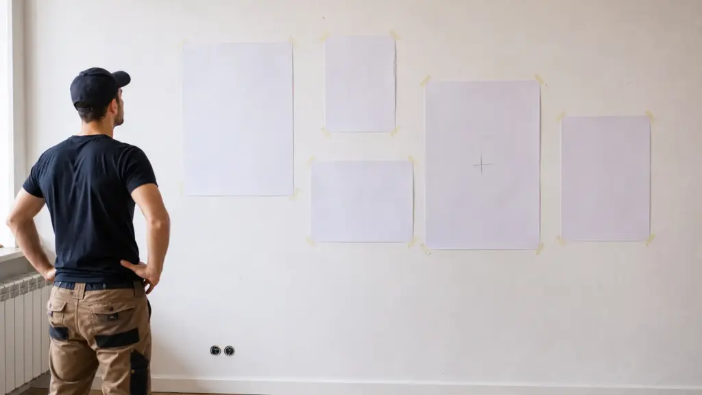 Mit Kreppband befestigte Papierschablonen an der Wand zeigen die geplante Bildanordnung