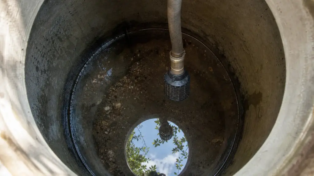 Saugschlauch mit Fußventil und Filterkorb hängt in einer Regenwasserzisterne über dem Boden