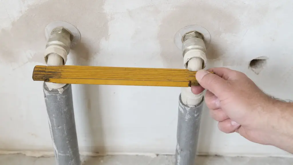 Heizkörperanschlüsse an der Wand, der Achsabstand wird mit dem Zollstock gemessen