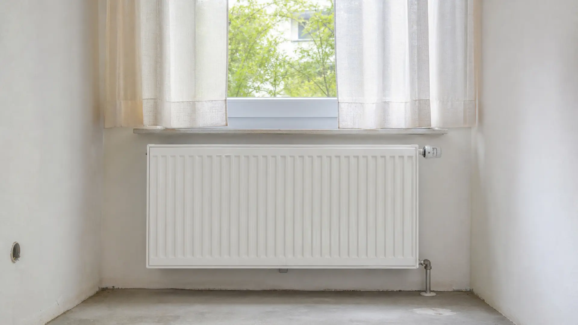 Freistehender Heizkörper unter einem Fenster, davor kein Möbel und kein Vorhang