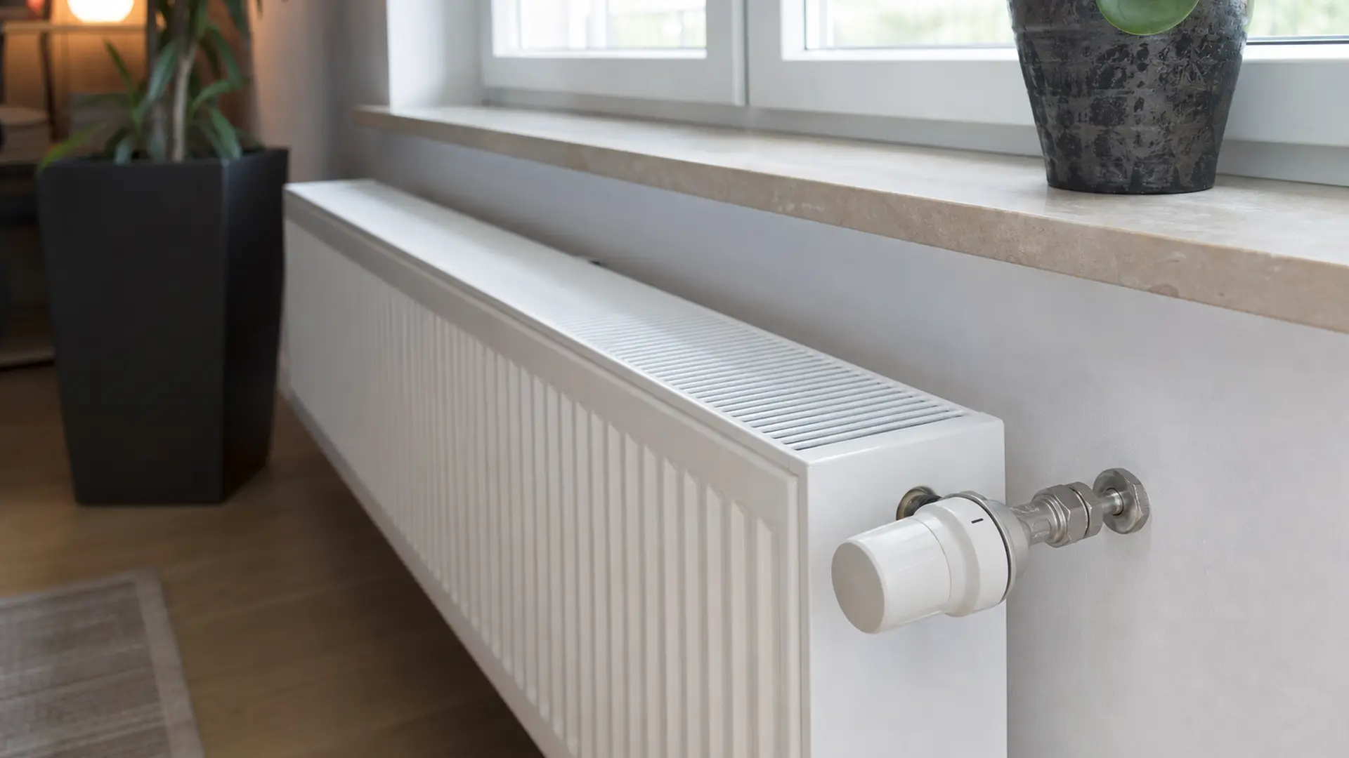 Programmierbares Thermostat an einem Heizkörper unter einem Fenster