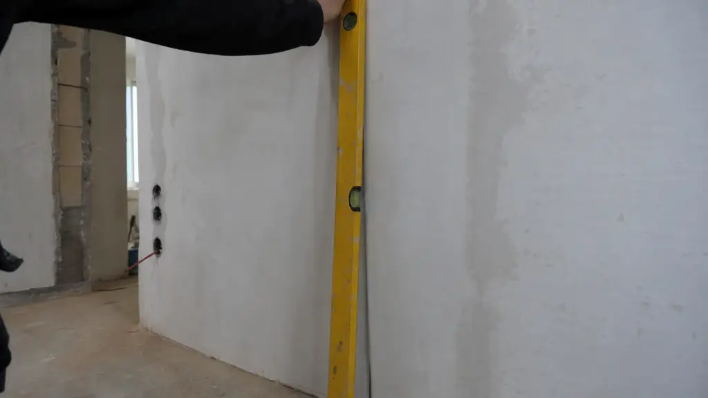 Lange Wasserwaage senkrecht an der Küchenwand, an der Unterkante ist ein deutlicher Spalt zur Wand sichtbar