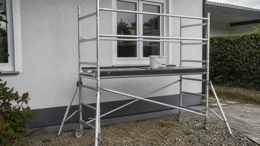 Fahrgerüst mit Seitenschutz und Bordbrett steht vor einer Hauswand