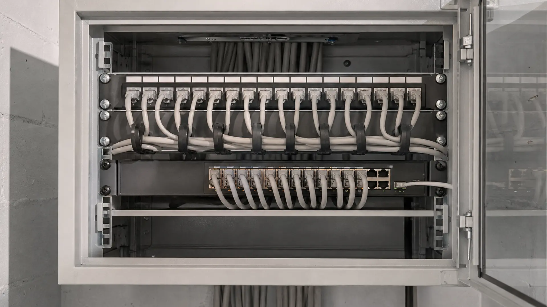 Aufgeräumter Wandnetzwerkschrank mit Patchpanel, Switch und Rangierpanel
