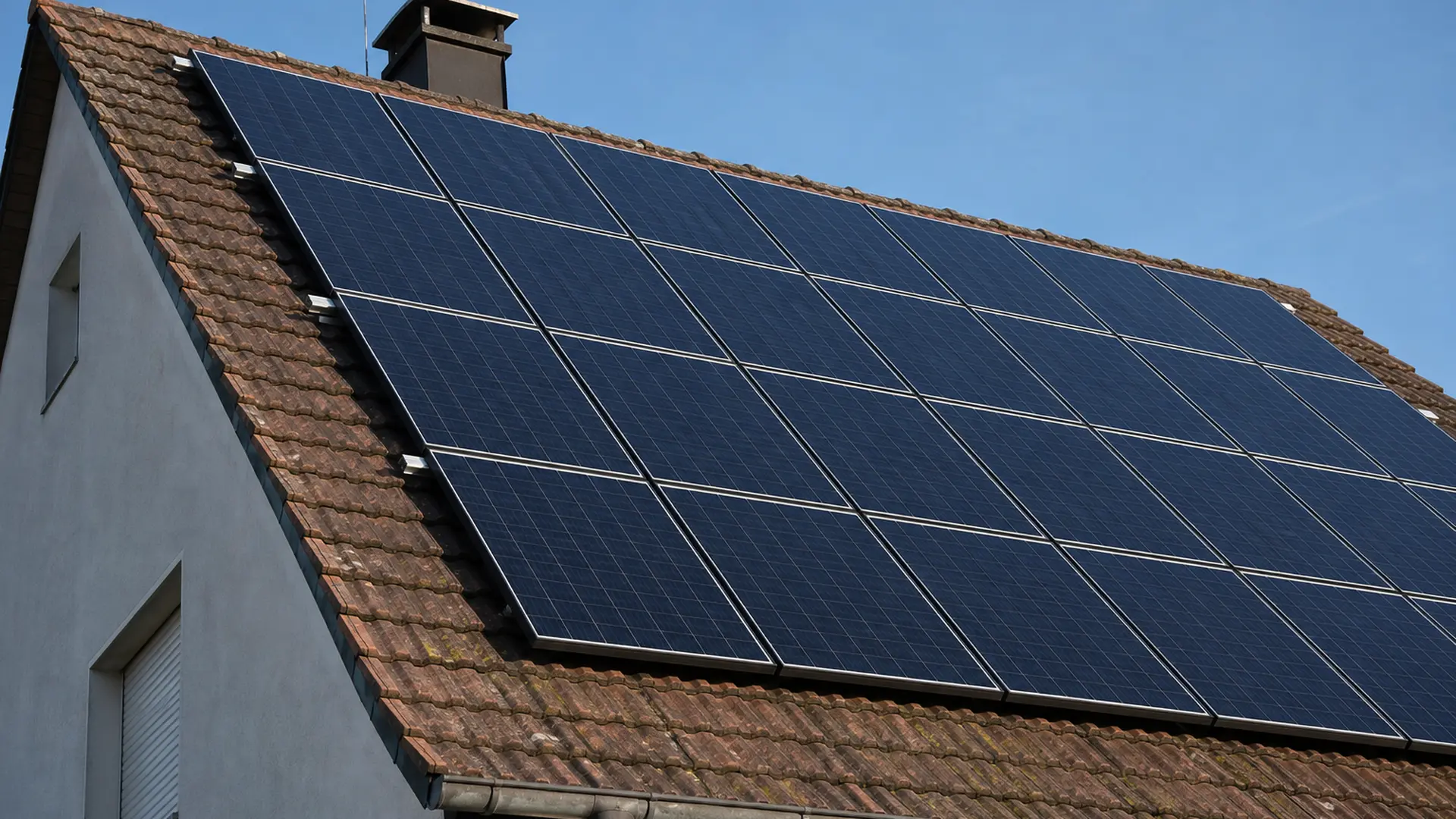 Photovoltaikmodule auf einem Satteldach eines Wohnhauses bei klarem Himmel