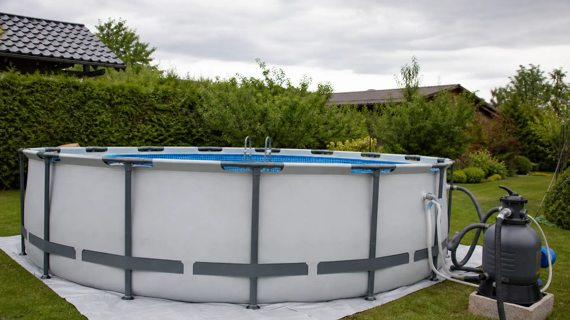 Runder Aufstellpool auf einer vorbereiteten ebenen Fläche im Garten, daneben die Filteranlage