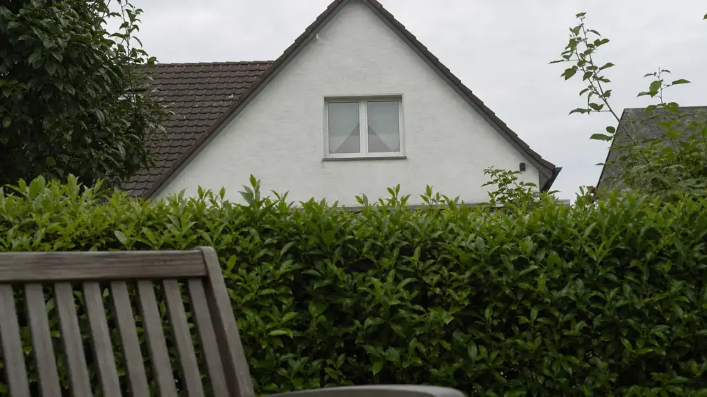 Blick von einem Gartenstuhl aus auf das Nachbarfenster, das über die Grundstücksgrenze sichtbar ist