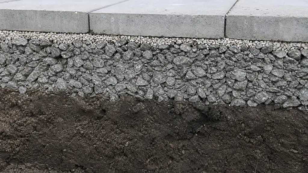 Angeschnittene Grube zeigt die Schichten aus Erdreich, Schotter, Splittbettung und Platten