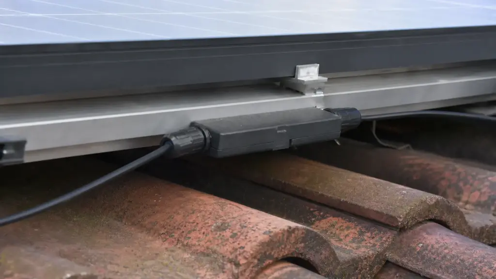 Leistungsoptimierer sitzt unter einem Solarmodul auf der Montageschiene