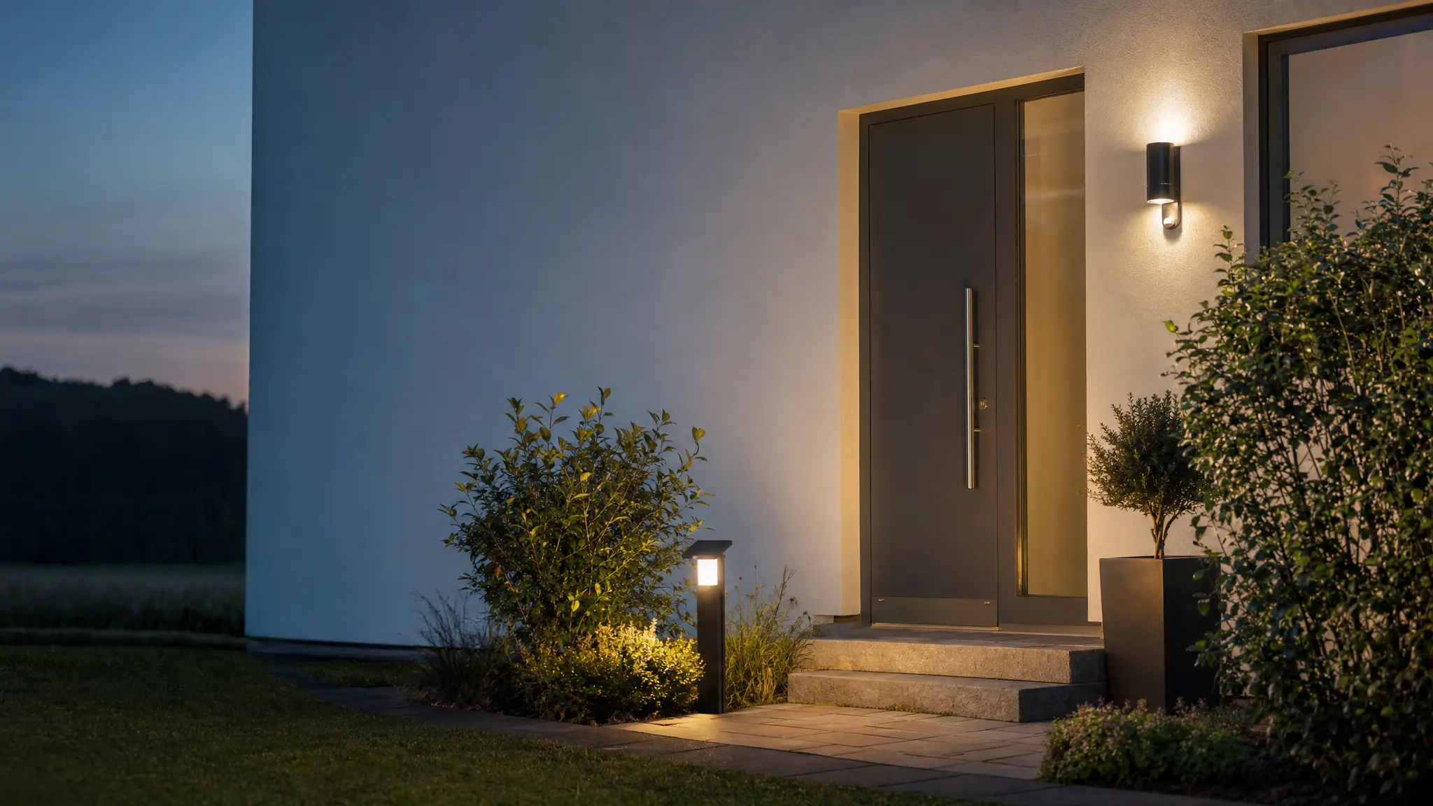 Eine Wandleuchte mit Bewegungsmelder an der Haustür und eine Solarleuchte im Garten in der Dämmerung